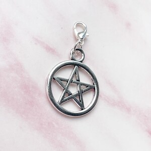 May include: Silver-toned pentagram charm with a lobster clasp. The five-pointed star is encircled by a ring. The charm is designed for use on a necklace, bracelet, or other jewelry.