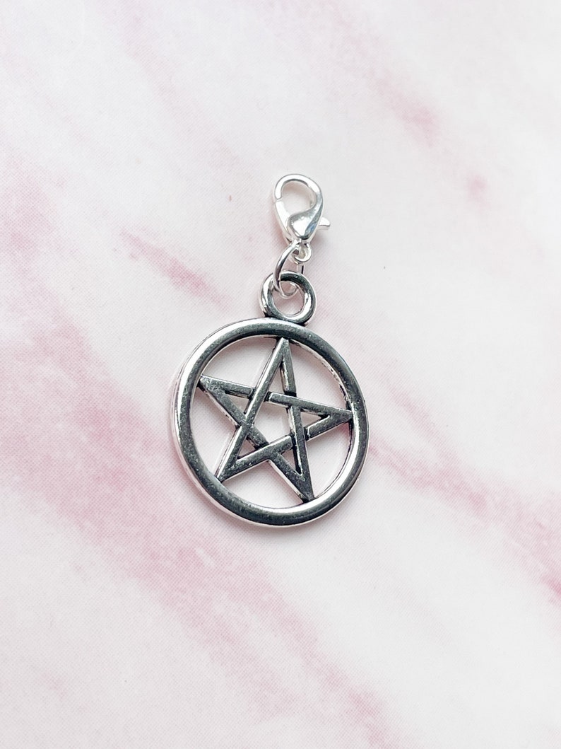 May include: Silver-toned pentagram charm with a lobster clasp. The five-pointed star is encircled by a ring. The charm is designed for use on a necklace, bracelet, or other jewelry.