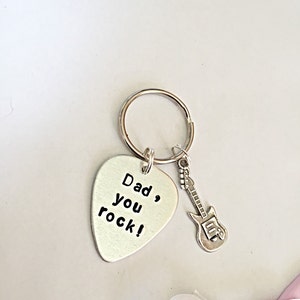 May include: Silver guitar pick keychain with the text "Dad, you rock!" and a small silver guitar charm.