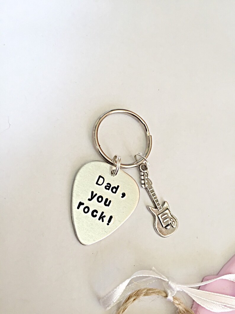 May include: Silver guitar pick keychain with the text "Dad, you rock!" and a small silver guitar charm.