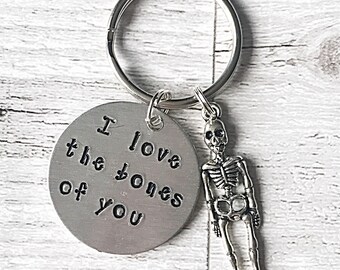 May include: Silver keychain with a round charm that says "I love the bones of you" and a small skeleton charm.