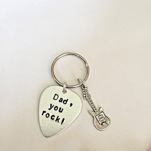 May include: Silver guitar-shaped keychain with a silver pick attached. The pick has the text "Dad, you rock!" engraved on it.