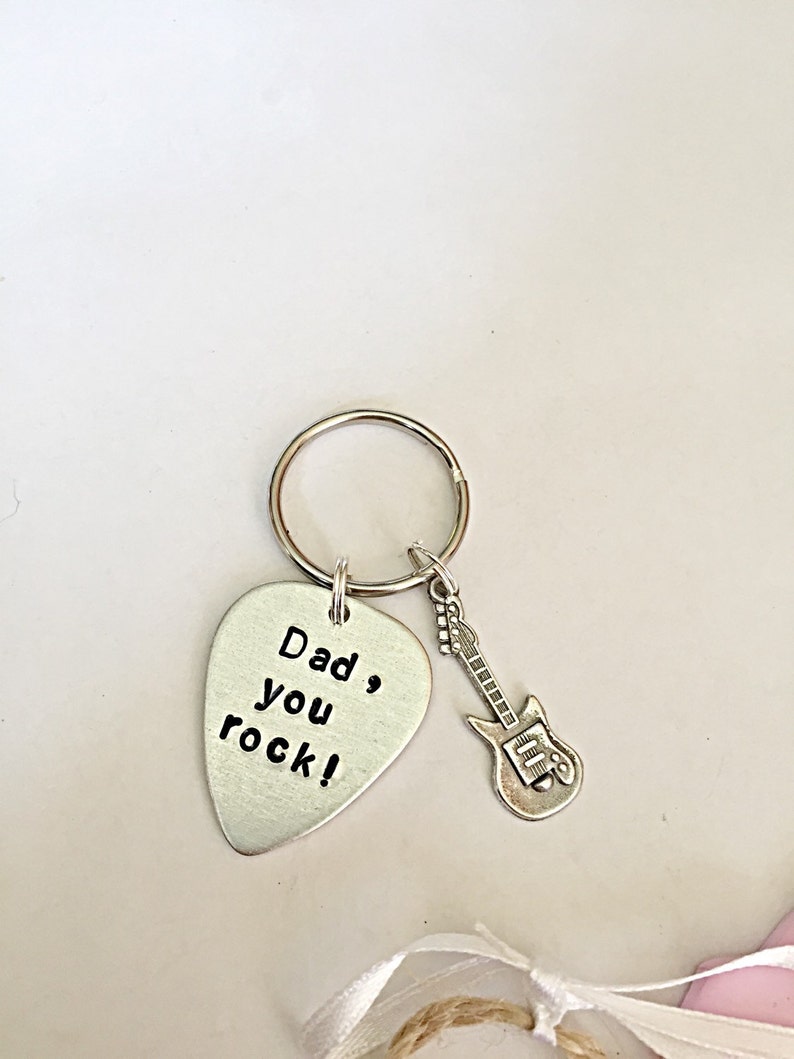May include: Silver guitar-shaped keychain with a silver pick attached. The pick has the text "Dad, you rock!" engraved on it.