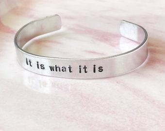 May include: Silver bracelet with the words "It is what it is" engraved on it.