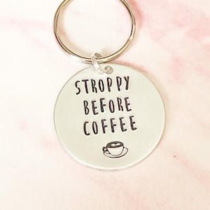 May include: Silver key chain with a round tag that says "STROPPY BEFORE COFFEE" with a small coffee cup icon.