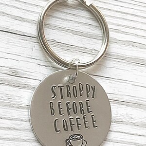 May include: Silver keychain with a round tag that says "STROPPY BEFORE COFFEE" with a small coffee cup icon.