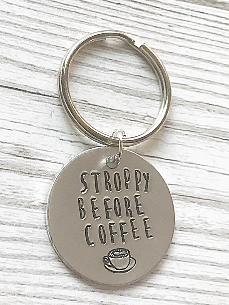 May include: Silver keychain with a round tag that says "STROPPY BEFORE COFFEE" with a small coffee cup icon.
