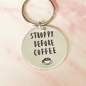 May include: Silver keychain with a round tag that says "STROPPY BEFORE COFFEE" with a small coffee cup icon.