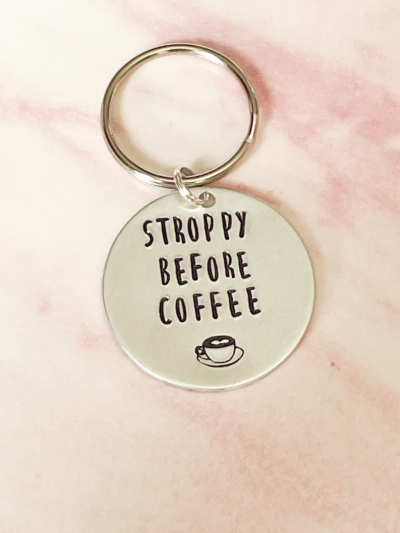 May include: Silver keychain with a round tag that says "STROPPY BEFORE COFFEE" with a small coffee cup icon.