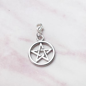 May include: A silver-colored pentagram charm with a lobster clasp. The five-pointed star is encircled by a ring. The charm is designed for use on a necklace, bracelet, or other jewelry.