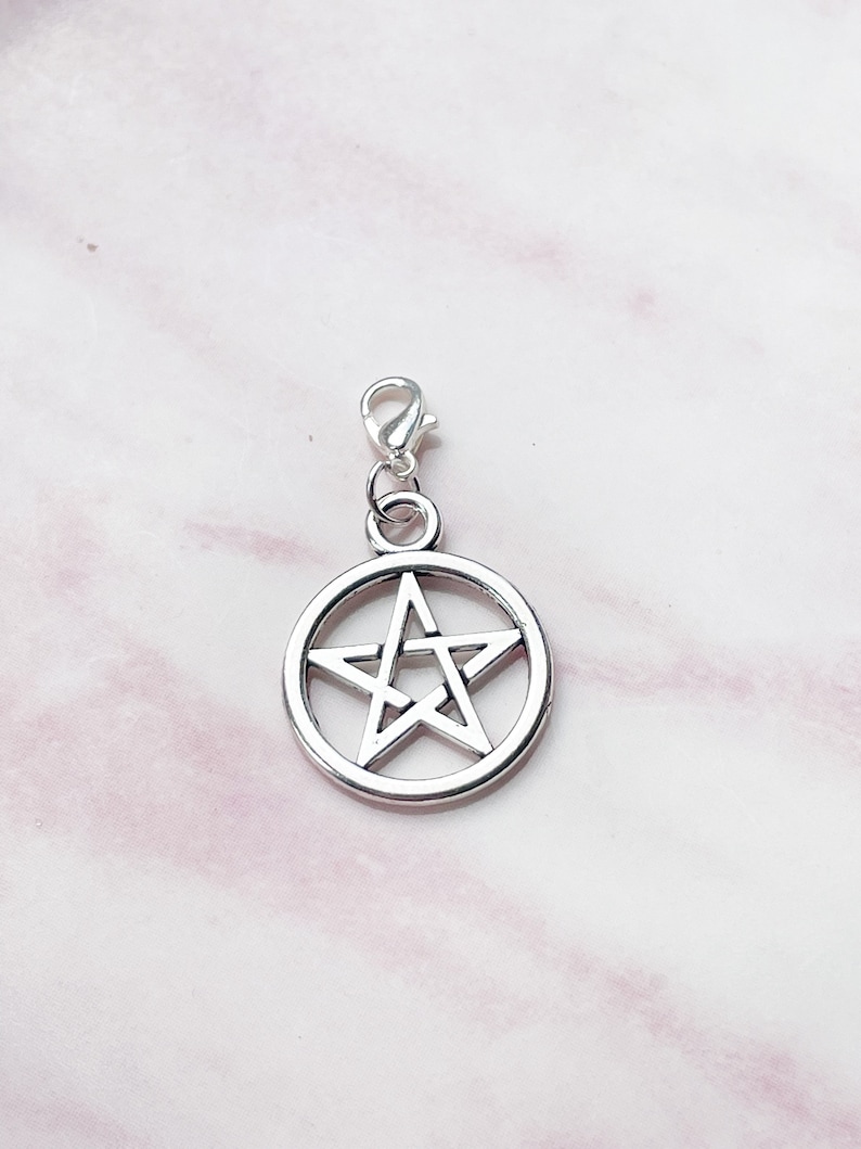 May include: A silver-colored pentagram charm with a lobster clasp. The five-pointed star is encircled by a ring. The charm is designed for use on a necklace, bracelet, or other jewelry.