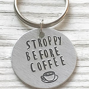 May include: A silver keychain with a round tag that says "STROPPY BEFORE COFFEE" with a small illustration of a coffee cup.
