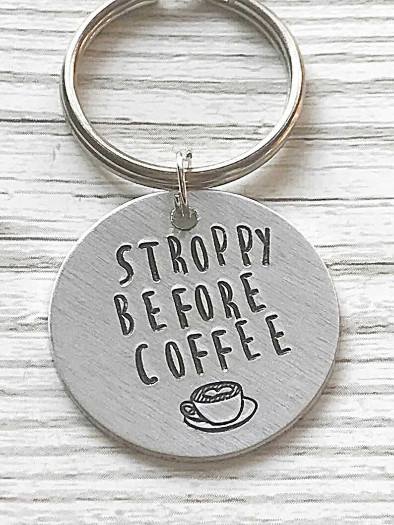 May include: A silver keychain with a round tag that says "STROPPY BEFORE COFFEE" with a small illustration of a coffee cup.