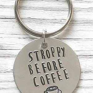 May include: Silver keychain with a round tag that says "STROPPY BEFORE COFFEE" with a small coffee cup icon.