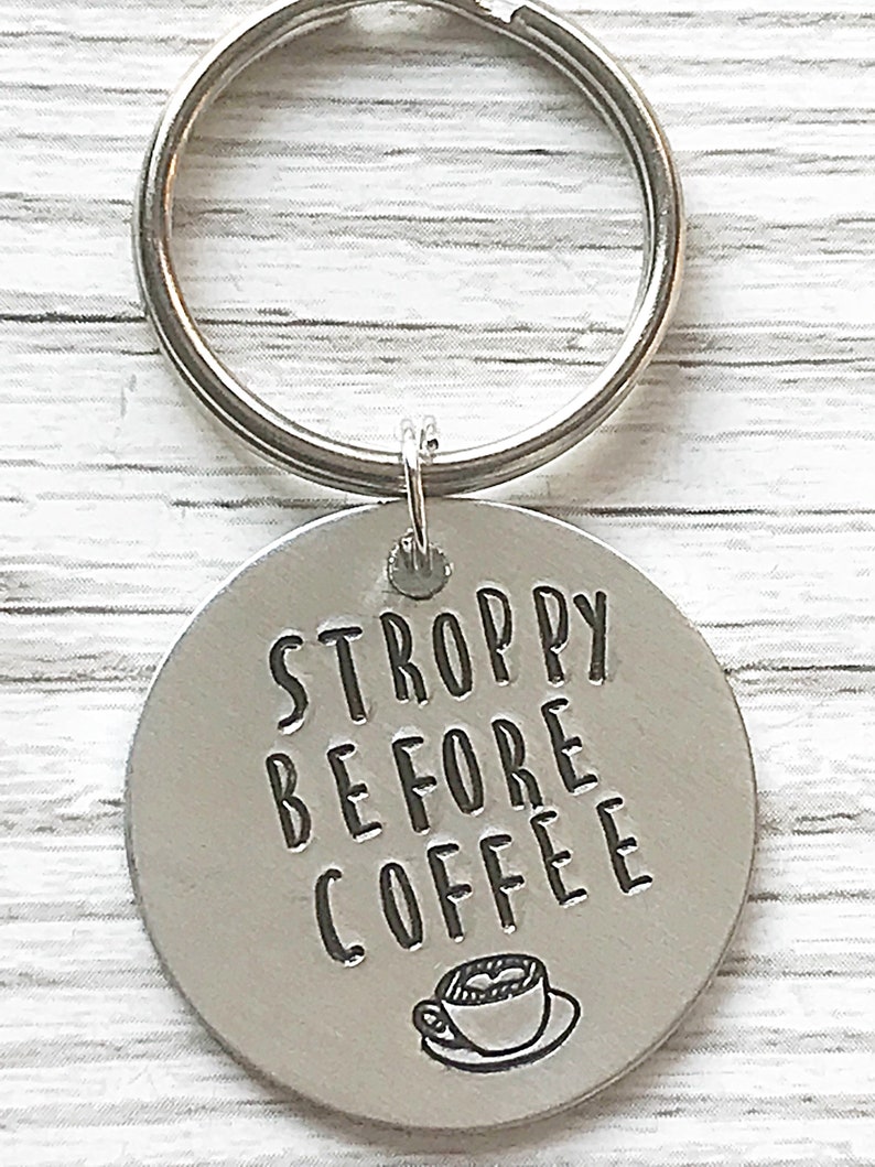 May include: Silver keychain with a round tag that says "STROPPY BEFORE COFFEE" with a small coffee cup icon.