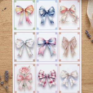 Può includere: Un foglio con nove illustrazioni ad acquerello di fiocchi, disposti a griglia. I fiocchi presentano vari disegni e colori, tra cui pastelli, rosa, blu e un motivo a quadri. Ogni fiocco è racchiuso in un bordo decorativo. L'immagine è su una superficie di legno con rametti di lavanda.