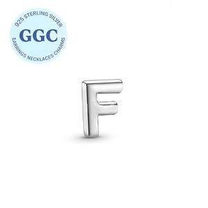 Può includere: Un ciondolo a forma di lettera "F" in argento lucido. Il ciondolo è una lettera maiuscola con un design arrotondato e squadrato. Un cerchio azzurro con il testo "925 STERLING SILVER" e "GGC" si trova nell'angolo in alto a sinistra. Il cerchio dice anche "EARRINGS NECKLACES CHARMS".