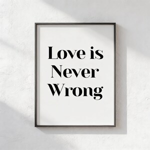 Peut inclure: Une affiche encadrée avec l'inscription "Love is Never Wrong" en caractères noirs gras. Le texte est centré sur un fond blanc, encadré par un fin cadre noir. L'œuvre est présentée sur un mur blanc texturé.