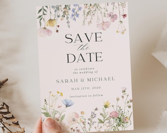May include: A floral wedding invitation with the text "SAVE THE DATE" in elegant script. The card features watercolor illustrations of wildflowers in pastel colors, with the names SARAH & MICHAEL and the date MAR 12TH. 2029.