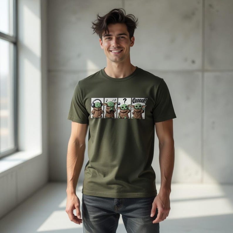 K&ouml;nnte beinhalten: Olivgr&uuml;nes T-Shirt mit einem Cartoon-Design von Grogu aus The Mandalorian. Das Design zeigt Grogu mit Kopfh&ouml;rern, Noten, einem Fragezeichen und dem Wort "Cooooool!" in einer Sprechblase. Das T-Shirt wird von einer Person getragen.