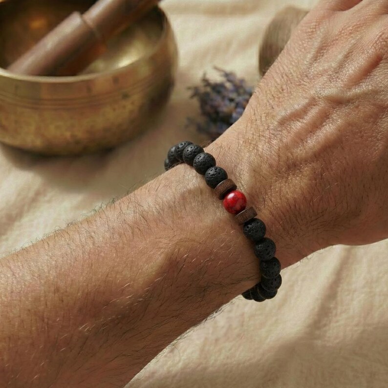 Unisex Perlenarmband mit rotem Stein am Handgelenk während einer Erdungs-Meditation.