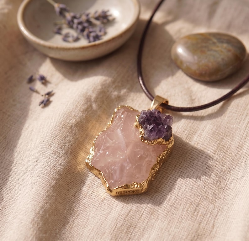 Nahaufnahme der natürlichen Kristallstruktur des Rosenquarzes und der violetten Amethyst Splitter in der goldenen Einfassung