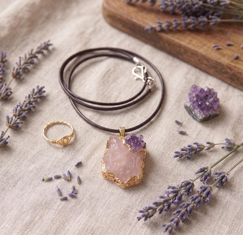 Nahaufnahme der natürlichen Kristallstruktur des Rosenquarzes und der violetten Amethyst Splitter in der goldenen Einfassung
