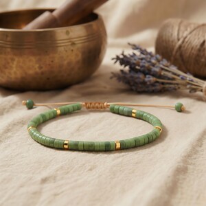 Serpentin Natursteinarmband liebevoll verpackt neben einem Beutel aus Naturfaser als achtsame Geschenkidee.