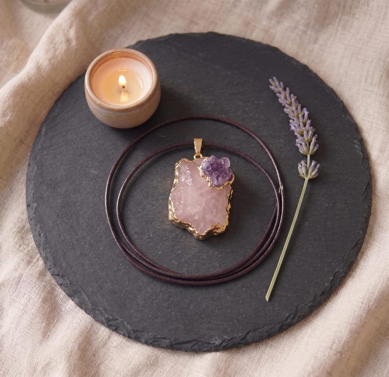 Talisman Kette mit Rosenquarz Amethyst flach liegend auf Schieferplatte neben brennender Kerze und Lavendelblüte