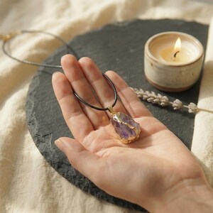 Lila Amethyst mit goldener Einfassung auf hellem Leinenhintergrund