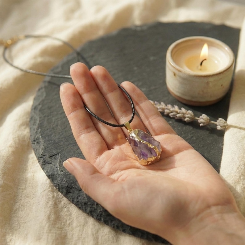Lila Amethyst mit goldener Einfassung auf hellem Leinenhintergrund