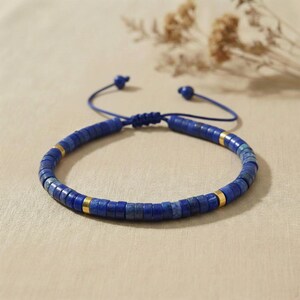 Eine Frauenhand mit dem blauen Naturstein-Armband in einer Yoga-Mudit-Pose (Gyan Mudra) über einer Klangschale, symbolisiert Meditation und Fokus.