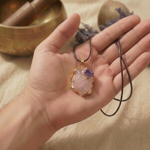Handfläche zeigt die Größe des ca 2cm großen Rosenquarz Rohsteins mit Amethyst Akzent in strukturierter Goldfassung