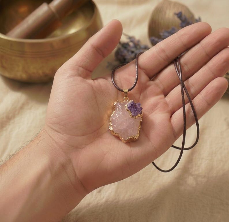 Handfläche zeigt die Größe des ca 2cm großen Rosenquarz Rohsteins mit Amethyst Akzent in strukturierter Goldfassung