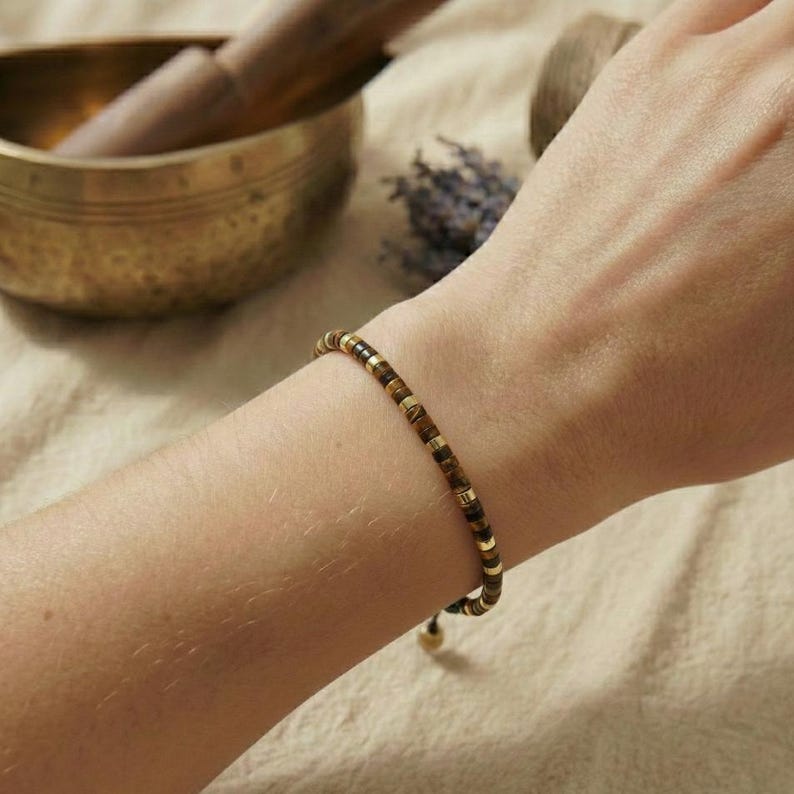 Chakra-Armband aus natürlichen Steinperlen dekorativ auf Naturleinen – bewusster Schmuck für Achtsamkeit & Balance, plastikfrei verpackt, in gold Tönen.