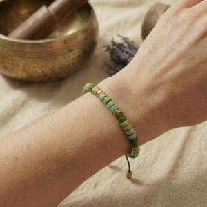 Zartes grünes Serpentin Flachperlen Armband getragen an einem Handgelenk im minimalistischen Boho Stil.