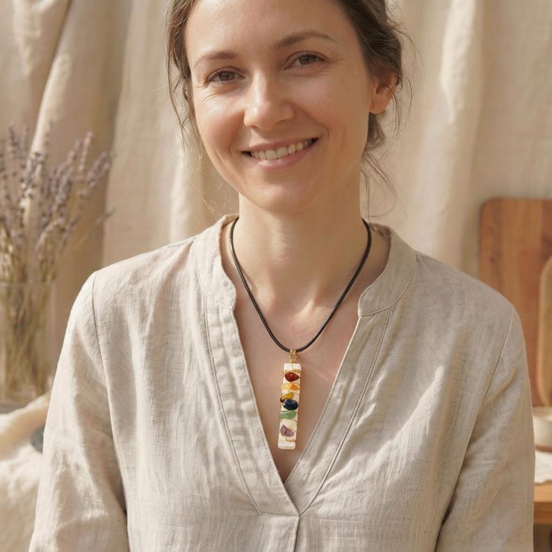 Frau im beigen Leinenhemd trägt die lange Selenit-Chakra-Kette mit echten Steinen als stilvollen Halsschmuck an einer Kunstleder Kette.
