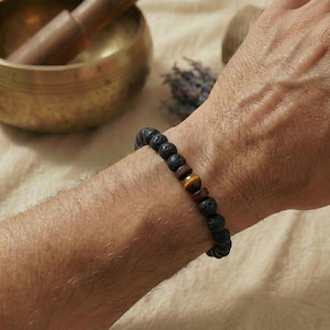 Lifestyle-Foto: Eine Person hält eine Tasse Tee, das Tigerauge-Armband ist am Handgelenk sichtbar (Stimmung: Fokus & Ruhe).