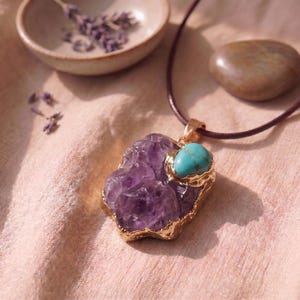 Detailaufnahme des großen rohen Amethyst-Talismans mit Goldfassung und leuchtendem Türkis-Stein auf naturfarbenem Leinentuch.