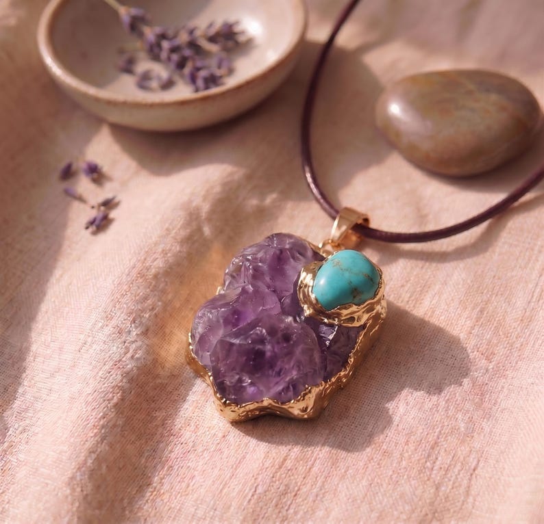 Detailaufnahme des großen rohen Amethyst-Talismans mit Goldfassung und leuchtendem Türkis-Stein auf naturfarbenem Leinentuch.