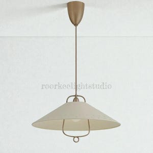 May include: A cream-coloured pendant light with a conical shade and a bronze-coloured metal frame. The light hangs from a matching bronze-coloured ceiling mount. The shade has small, decorative perforations. The text "roorkeelightstudio" is visible.