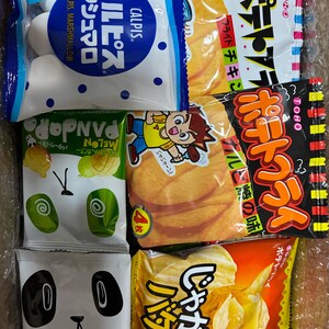 Peut inclure: Assortiment d'en-cas japonais dans des emballages color&eacute;s. Comprend des guimauves Calpis, des chips de pommes de terre et des biscuits au beurre en forme de panda. Les snacks sont dans une bo&icirc;te en carton.