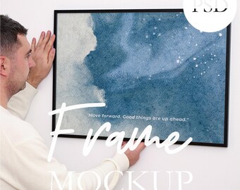 Puede incluir: Una impresión artística enmarcada en negro con un diseño de acuarela azul y blanco está siendo sostenida por una persona. La impresión tiene las palabras "Move forward. Good things are up ahead." y la palabra "Frame" en una fuente de escritura. La palabra "MOCKUP" también es visible.