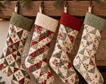 May include: Four quilted Christmas stockings hanging in a row. Each stocking features a patchwork design of triangles in red, green, and cream fabric with various holiday patterns. The cuffs are solid colors in olive green, cream, and deep red.