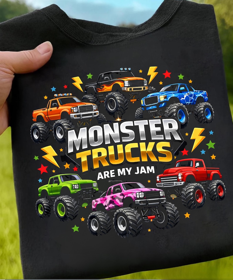 May include: Black t-shirt featuring a colorful graphic of seven monster trucks in various colors, including orange, blue, and green. The text "MONSTER TRUCKS ARE MY JAM" is prominently displayed.