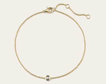 May include: A delicate gold chain bracelet with a small, round diamond pendant. The bracelet features a lobster clasp closure and an adjustable chain for a customized fit. The jewelry is displayed on a neutral background.