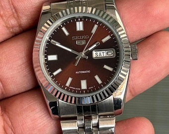 Orologio Seiko 5 Automatico Vintage, quadrante marrone a raggiera, lunetta scanalata, datario con indicazione di giorno e data.