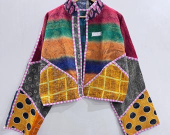 May include: A long-sleeved jacket featuring a patchwork design with horizontal stripes in red, green, orange, and blue, yellow grid patterns, and black sections with white polka dots. The garment has a stand-up collar and a white tag labeled KV51.