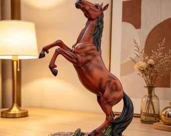 May include: A brown horse statue rearing up on its hind legs. The horse has a black mane and tail, and is mounted on a textured base. The statue is a decorative item, suitable for home decor.