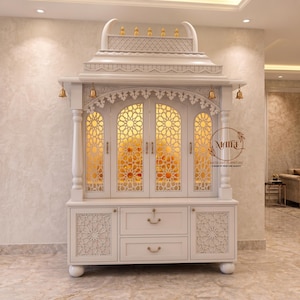 May include: A white wooden cabinet with intricate geometric cutouts and a domed top. The cabinet features multiple doors and drawers, with decorative bells and gold accents. The interior glows with warm light, suggesting a display or storage space.